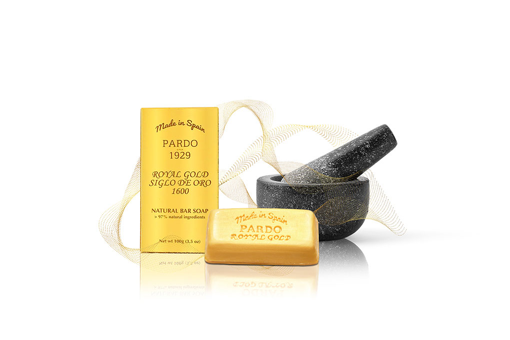 Pardo Royal Gold Jabón dorado y su caja color dorado detrás junto a un lazo dorado y un mortero negro de artesano jabonero